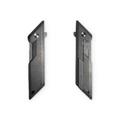 Two slim black utility knife blades shown side by side on a plain white background, displaying both the serrated and unserrated sides.
