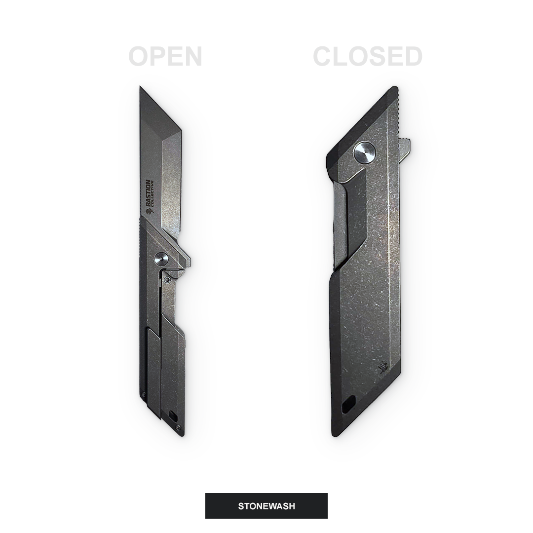 A black metal utility knife shown in two positions: open on the left and closed on the right, labeled 'OPEN' and 'CLOSED' with a 'STONEWASH' label at the bottom. The knife has a textured, stone-washed finish.