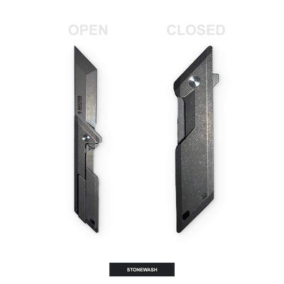 A black metal utility knife shown in two positions: open on the left and closed on the right, labeled 'OPEN' and 'CLOSED' with a 'STONEWASH' label at the bottom. The knife has a textured, stone-washed finish.