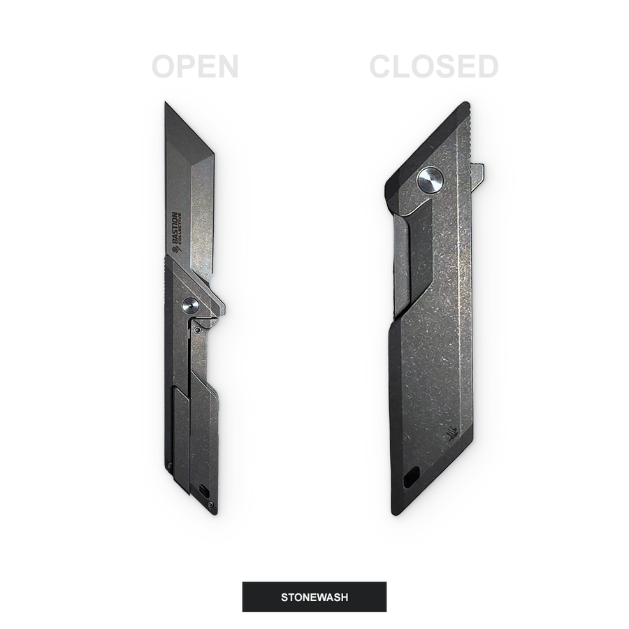 A black metal utility knife shown in two positions: open on the left and closed on the right, labeled 'OPEN' and 'CLOSED' with a 'STONEWASH' label at the bottom. The knife has a textured, stone-washed finish.