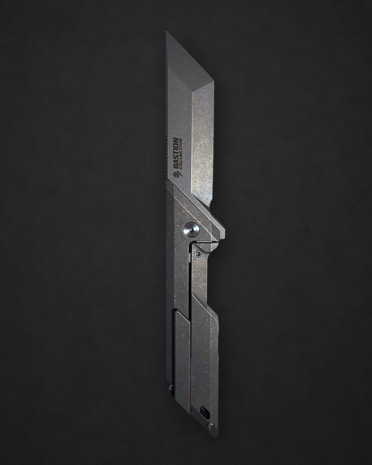 A tactical utility knife with a metallic silver blade and matching metal handle, shown vertically against a dark textured background.